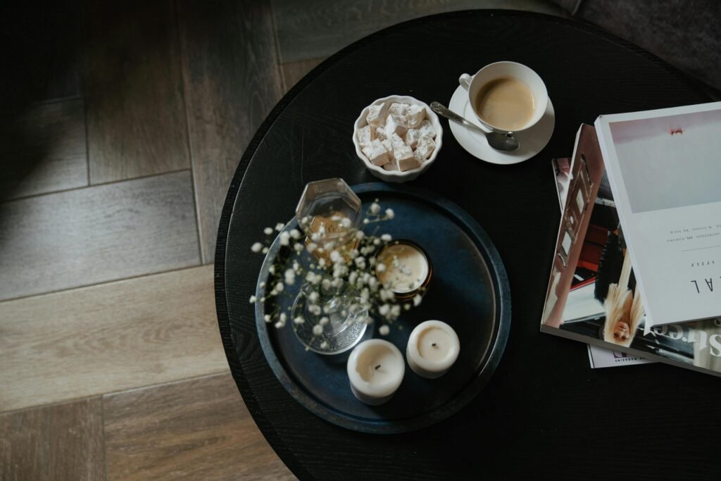 A serene coffee break setting with books, candles, and sweet treats on a round table.